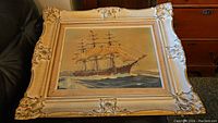 Front view of framed oil painting showing the sailing ship on ocean.
