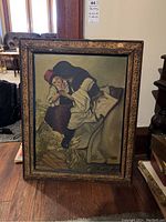 Full view of framed painting propped against wall