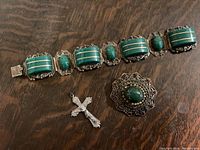 Overall view of bracelet, brooch, and cross pendant displayed on a wooden surface.