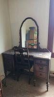 Front view of antique vanity and matching chair in room corner