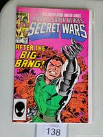 Front cover of the Marvel Superheroes Secret Wars #12 comic book showing character and series information with bright pink background.