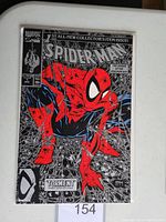 Front cover of Spider-Man #1 comic book showing black and silver design with red and blue Spider-Man crouched among spider webs.