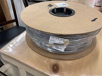 Photo showing a large spool with approximately 100 feet of gray rubber hose labeled PSVTR 75-100 B.
