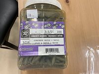 Plastic container of 100 Ramset 3 1/2 inch concrete anchors with product label visible.