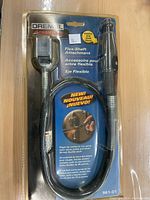 Front view of sealed retail blister pack showing Dremel Advantage branding and model 961-01 flex-shaft attachment with packaging details and usage image.