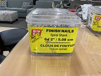 Plastic container with label reading Grip Rite Finish Nails Spiral Shank 6d 2" / 5.08 cm, 1.5 kg