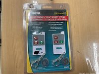 Blister pack containing two Ideal brand remote control fobs for security systems, model SK629, with buttons for arming and disarming, keychains attached, original packaging and instructions visible