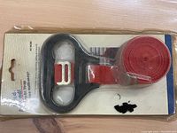 Photo of a Lend-a-hand carry all strap in original packaging showing red nylon strap and black plastic handle.