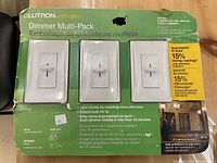 Original retail packaging for the Lutron Dimmer Multi-Pack showing three white Lutron Skylark eco-dim dimmers and three Clark wall plates inside clear plastic window.