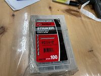 Box of 100 Striker brand #12 x 4 1/2 inch concrete nails in sealed clear plastic container with label.