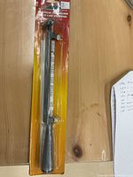 Laser branded universal file holder tool in original packaging on wooden surface.