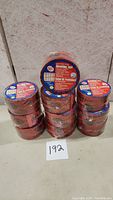 10 rolls of red Tuck Tape sheathing tape stacked and sealed in plastic.