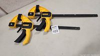 Two Dewalt quick-release work clamps on a table.