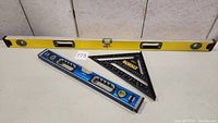 Photo showing full set of two levels and one speed square on flat surface.