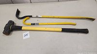 Overview of all three heavy duty construction tools on a table: sledgehammer and two crowbars.