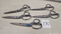 Five pairs of 10 inch Gingher cutting scissors arranged on white surface