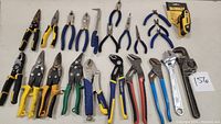 Overview of the multi tool lot showing mostly pliers and cutters on a white surface, arranged in a line.