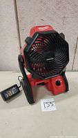 Front view of the Milwaukee 18V jobsite fan showing the black protective grill, control knob, and power cord connected.