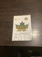 Front cover of the 2019 Canadian coin set packaging featuring a maple leaf shaped cutout revealing a specially designed coin and commemorative artwork.