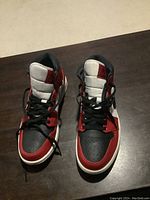 Pair of red, white and black Air Jordan 1 sneakers viewed from above on dark wood surface