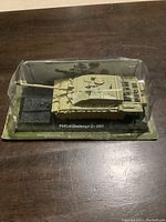 Front angle image showing the diecast model tank in original packaging on a clear base labeled FV4034 Challenger 2 - 2003.