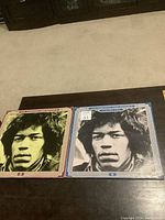 Two LP records with Jimi Hendrix cover art placed side by side on a dark wood table, showing the front covers.