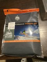 Packaged Outland Optimal Performance Thermal Set top folded in plastic packaging, showing brand name, size XXL, and marketing text.