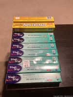 Top-down photo of assorted rolls of plastic wrap and one box of wax paper stacked on the floor.