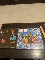 Two Rolling Stones LP albums on table, left '12 x 5', right 'Their Satanic Majesties Request'.