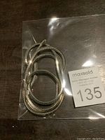 Silver plated link chain folded inside a plastic bag with auction tag, showing texture and link pattern.