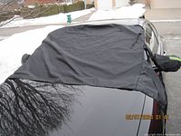 Black windshield snow cover placed over car windshield and hood area, showing overall coverage and fit.