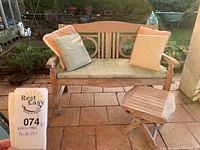 Front view of teak bench with cushions and side table on tiled patio