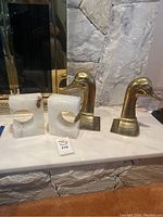 All four bookends arranged on a marble hearth: two white onyx stone pieces on left and two brass duck head pieces on right.