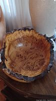Front view of burled wood bowl showing natural bark edge and wood grain pattern.