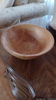 Front view of the burled wood bowl placed on a wooden table showing the interior patterns and shape.