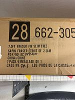 Cardboard box with label stating 7.5 foot Fraser Fir slim plastic Christmas tree, weight, and manufacturing details from China