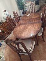 Oval solid pecan wood dining table with starburst woodgrain pattern and six matching chairs.