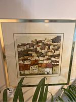 Front view of the framed art print showing houses on a hill with metallic frame and matting.