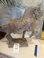 Side view of the horse statue showing its textured and distressed finish and raised front leg.