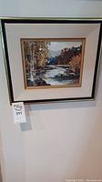 Front view of framed oil painting showing autumn river landscape with forest