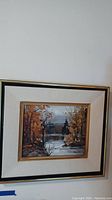 Overall view of framed autumn landscape painting with trees by a lake