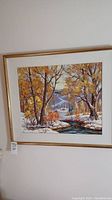 Framed painting hung on wall showing winter landscape scene