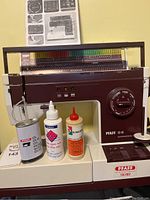 Full view of Pfaff Syncrotronic 1229 sewing machine and three bottles of oil/glue on built-in shelf