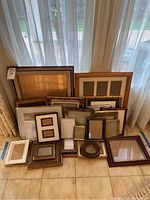 Full lot of picture frames arranged on tile floor near window with curtains.