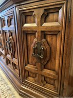 Close-up of the wood panel door with decorative metal hardware showing the carved wood details and metal handle.