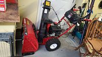 Side profile of assembled snow blower showing housing, chute, tires and controls