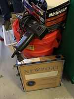 Mastercraft angle grinder in its box on top of an orange plastic bucket with a cardboard box beneath