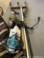 Photo showing blue Makita sander with attached power cord, alongside other tools with cables coiled