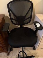 Full view of the black office chair showing the mesh back, padded seat and armrests