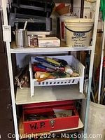 White shelving unit holding a bucket of drywall compound, paint trays, and a basket of painting tools.
